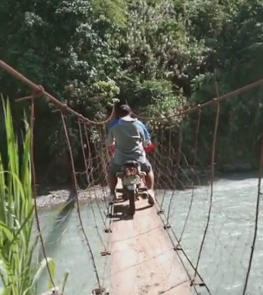 Motorcycle crossing a hanging bridge in a rural community in the Philippines